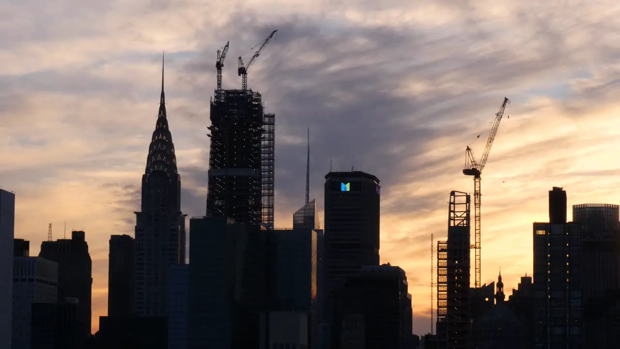 Establishing shot of Chrysler building the Metlife building and the construction of new skyscrapers at sunset while a helicopter flying by in the background in New York City