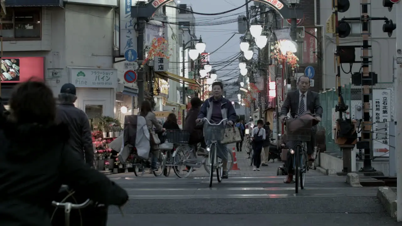 Street view of a Tokyo city market people crossing road with the bicycles during a late evening