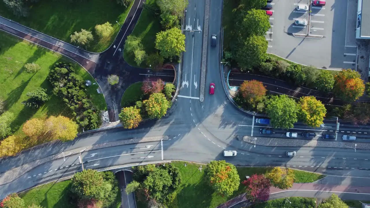 Overhead aerial looks down onto city traffic driving at T intersection