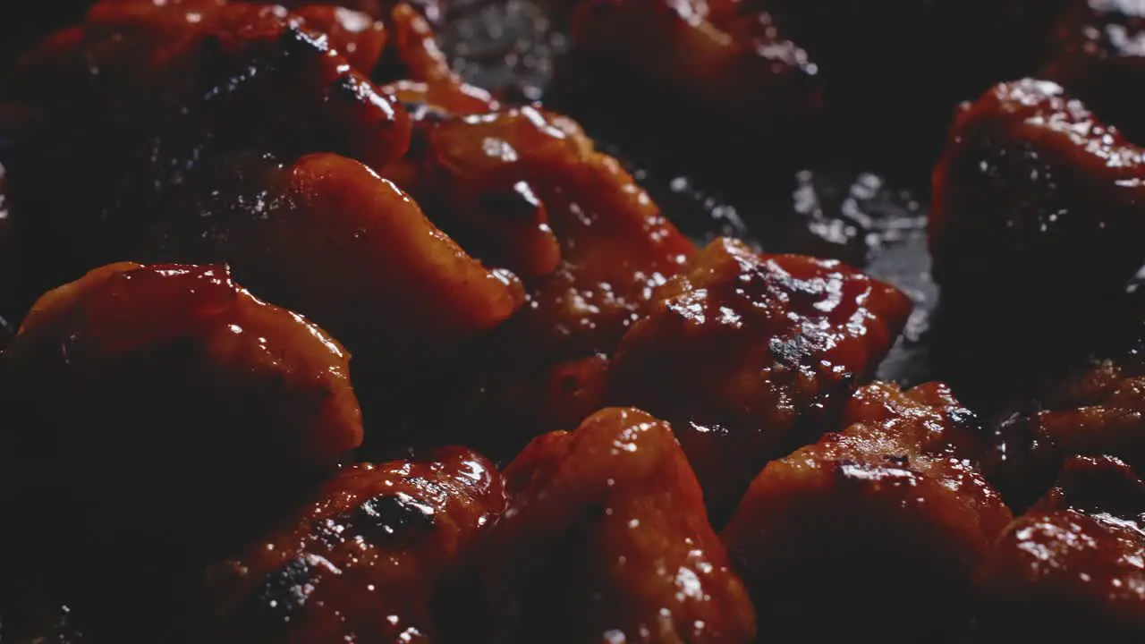 Macro shot of sweet and sour chicken pieces into a frying pan