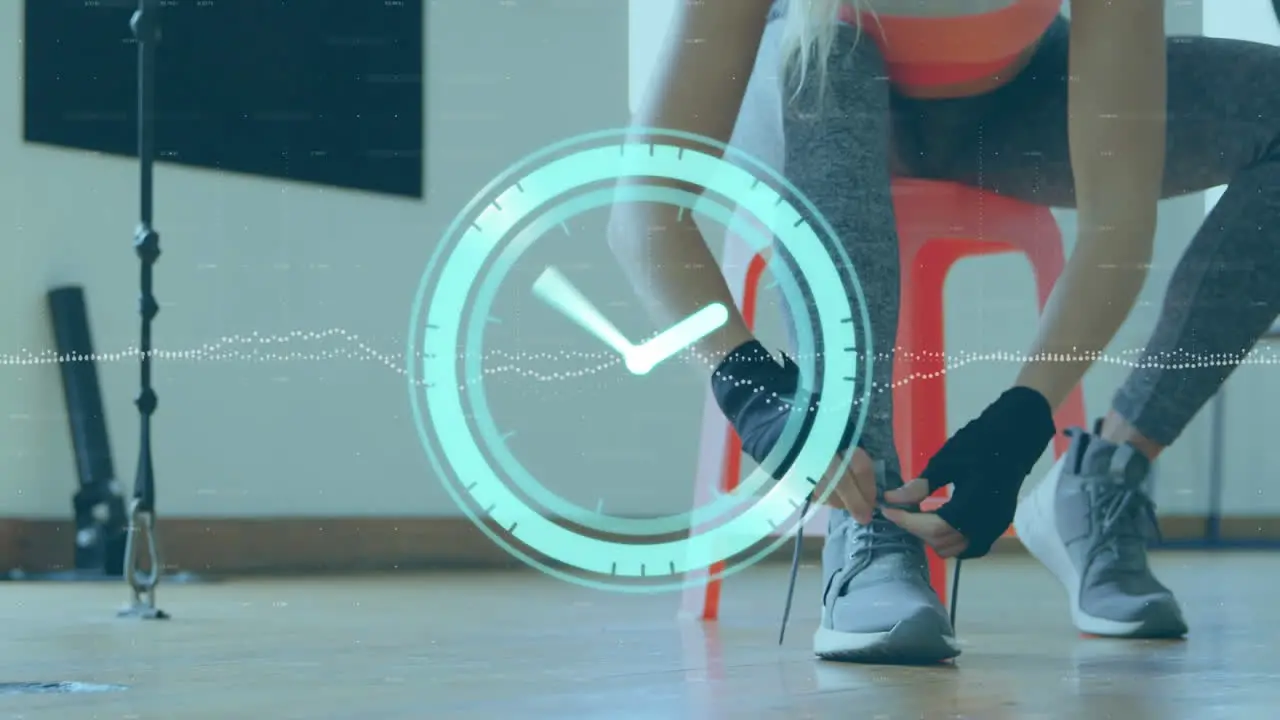 Animation of neon ticking clock against mid section of female boxer tying shoes laces at the gym