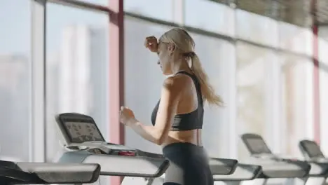 Running woman practicing on treadmill machine in fitness gym