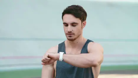 Sport man looking smart watch at modern track Man runner using smart watch