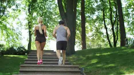 Running couple climbing stairs at morning run in summer park