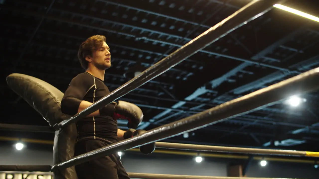 Handsome fitness man having rest in sport club Boxer standing on boxing ring