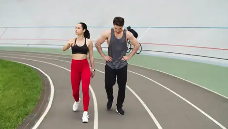 Exhausted couple having break after training together on athletics track