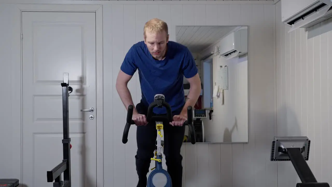 Middle aged caucasian man workout on bike in home-gym front view