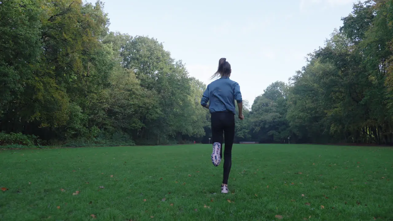 Mesmerizing slow-motion shot of a woman running over a grassy field with the camera gracefully following her