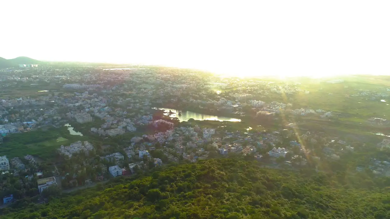 Drone shot moving backwards and panning with a mountain and sunset with shifting solar flare