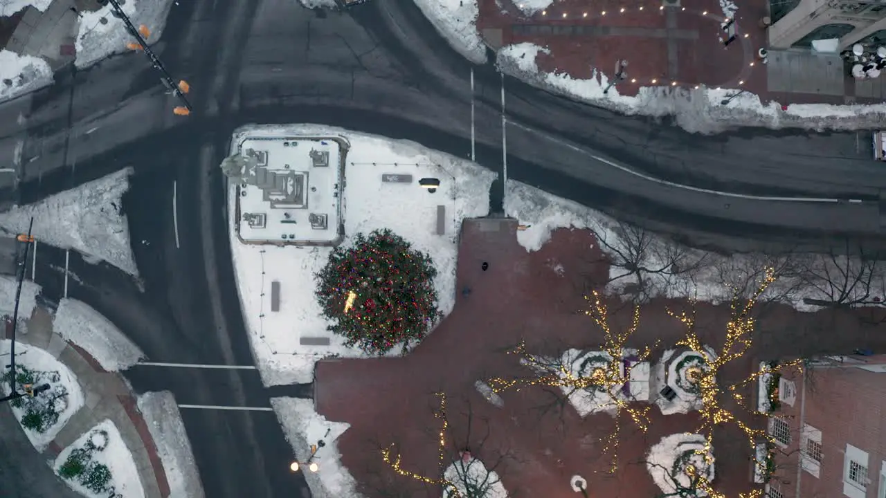 Descending top down aerial of decorated Christmas tree and lights in downtown city