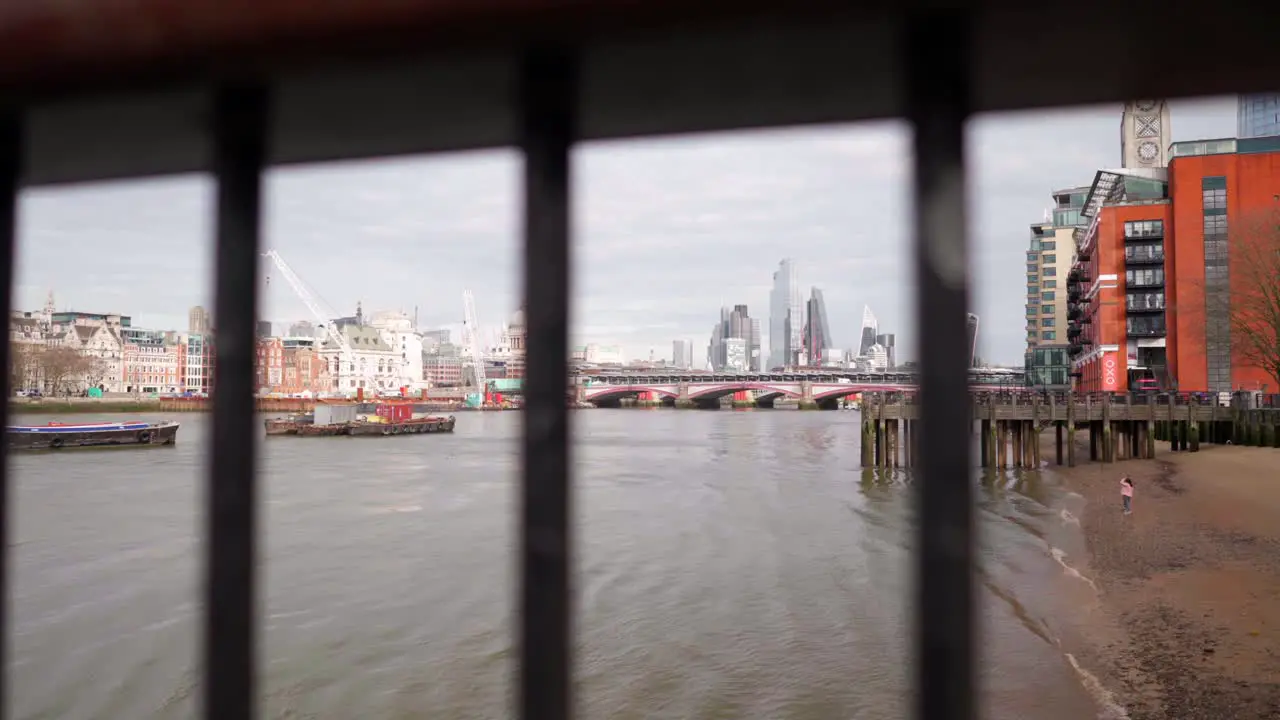 London City skyline view from the river Thames through a fence in slow-motion