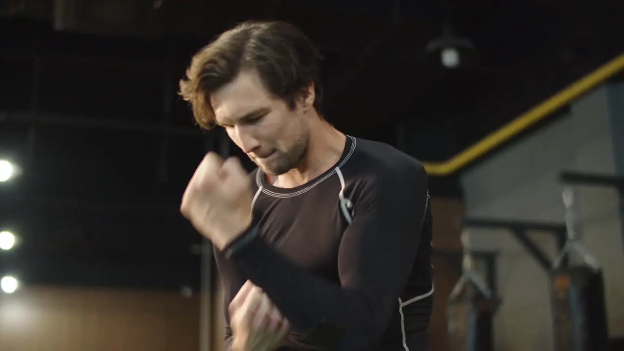 Active sport man preparing for fight in fitness center Boxer warming up at gym