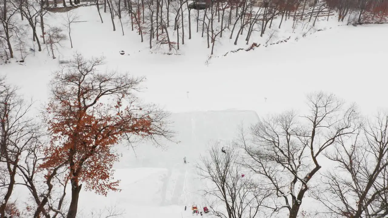 Aerial family and friends skating on outdoor homemade ice rink on frozen lake