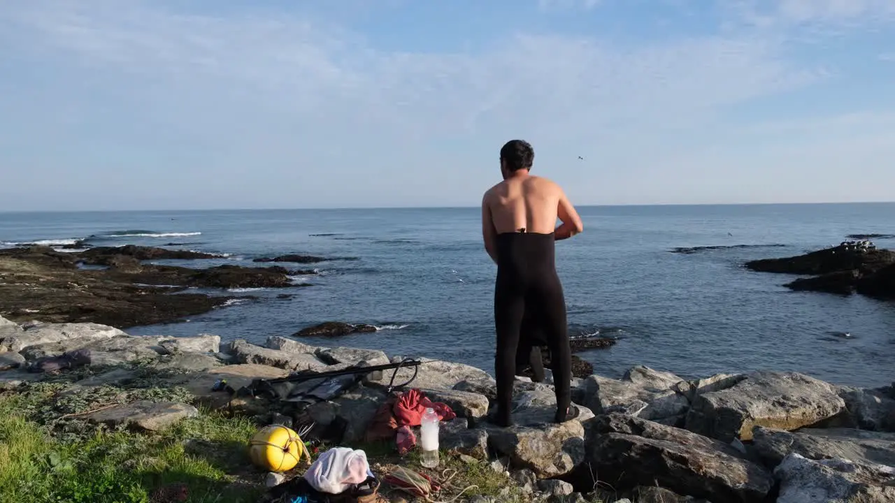 Spearfisher getting dressed to go hunting while watching the sea at Duao beach in the Maule region of Chile at sunrise