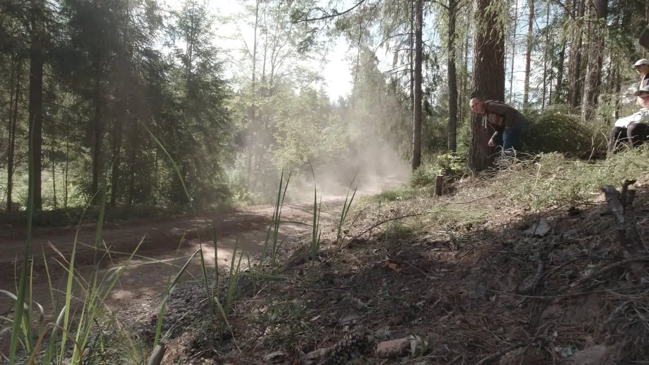 WRC rally in Estonia fast rally car fly s bye on high speed on gravel road surrounded by forest dust cloud is seen in sunlight