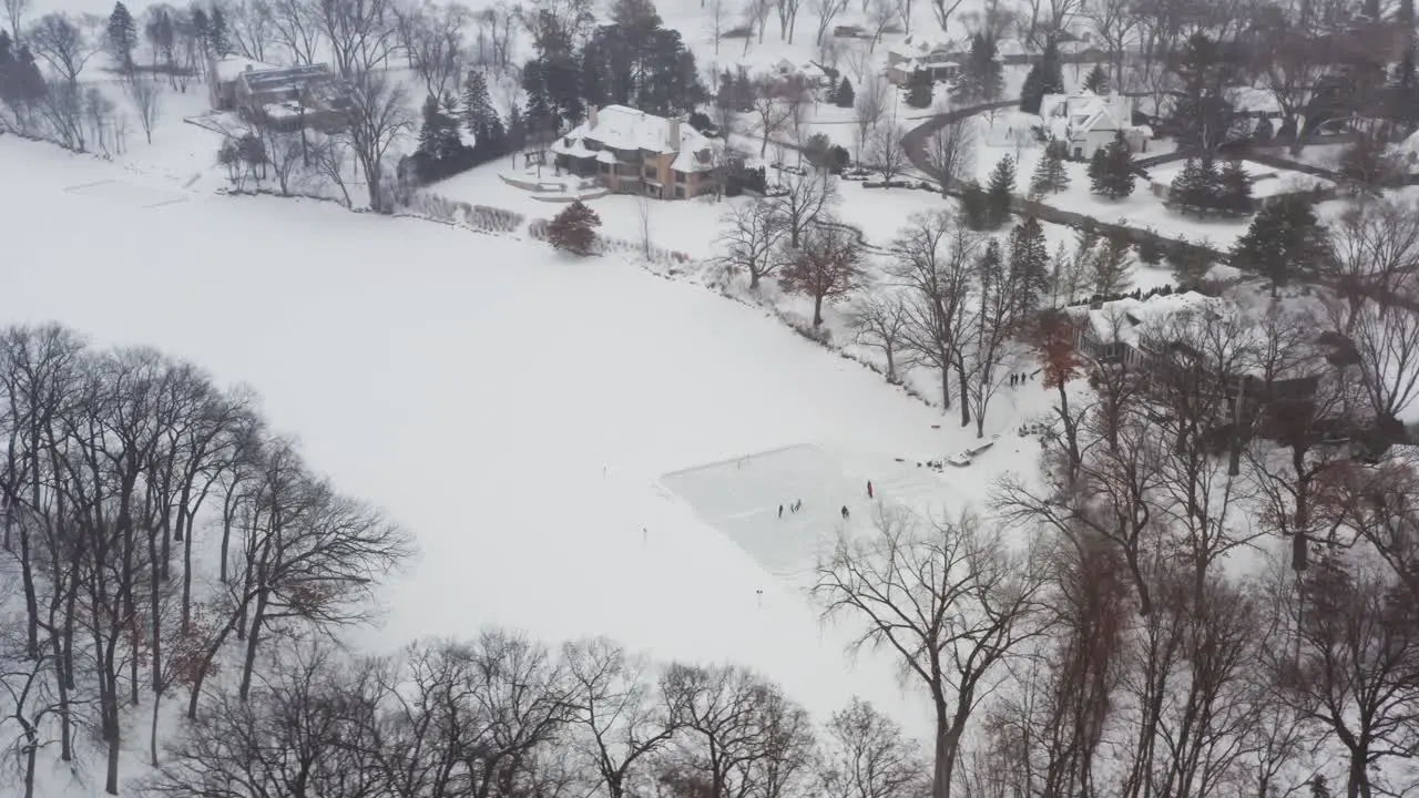 Aerial friends and family skating on a homemade ice rink in backyard lake pond