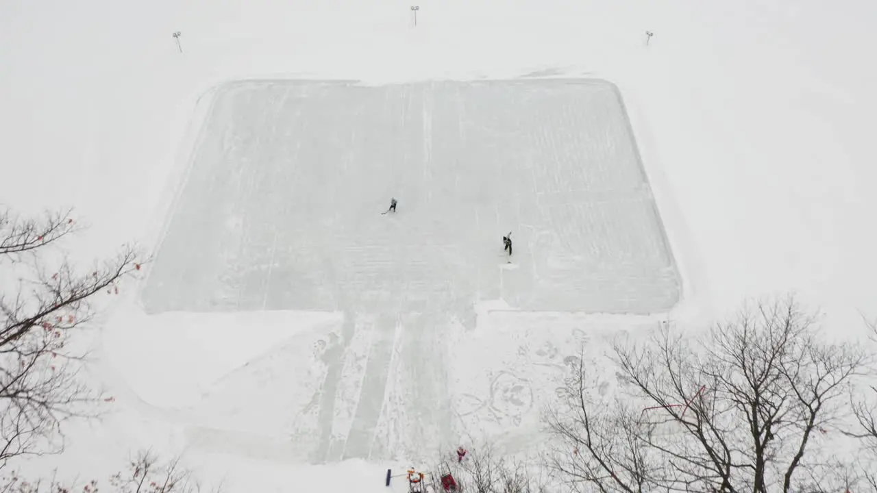 Aerial two people playing ice hockey outdoors on an ice rink made on frozen lake