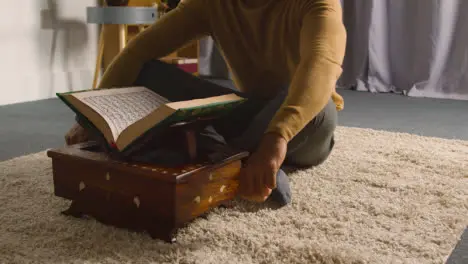 Close Up Of Muslim Man At Home Sitting On Floor And Reciting From The Quran