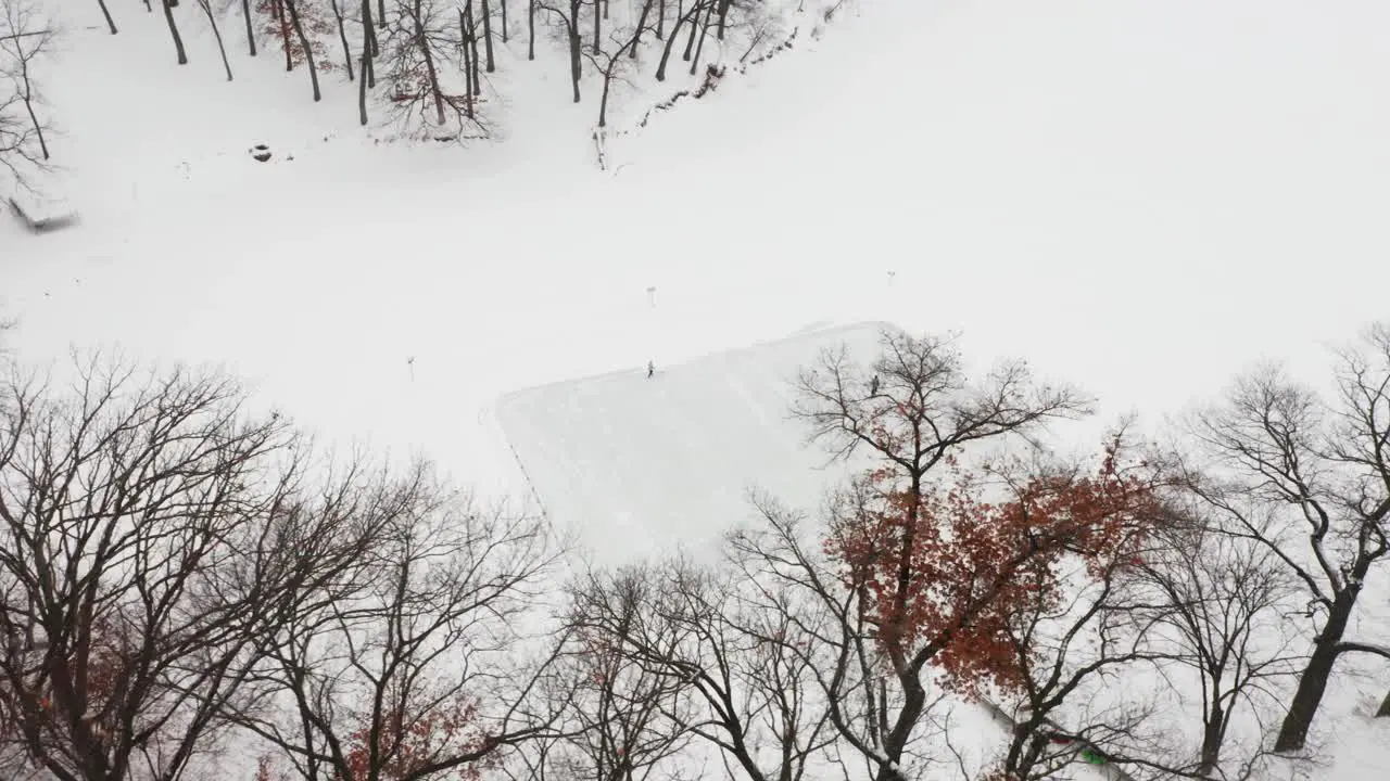 Aerial two people playing ice hockey on a small ice rink made on frozen lake