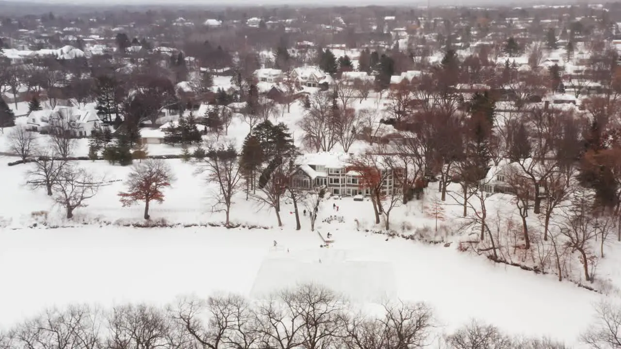 Aerial family and friends ice skating on outdoor homemade ice rink in backyard pond frozen lake