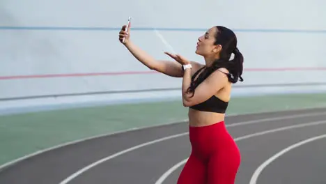 Runner woman taking selfie photo on mobile phone at modern track