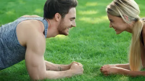 Happy couple training plank exercise in summer park Sport couple concept