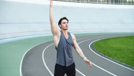 Male runner warming up before running workout on track Fit man stretching hands