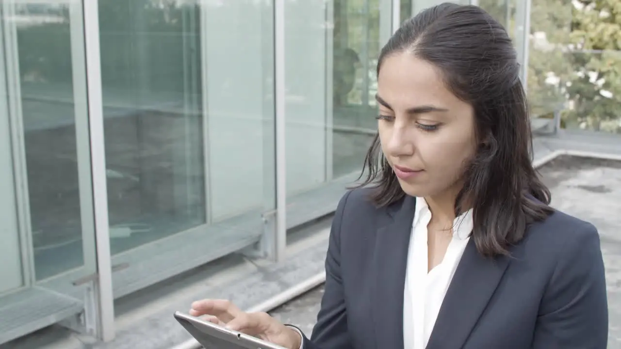 Vertical Motion Of A Pensive Latin Businesswoman In Suit Using Tablet For Work While Walking Outside