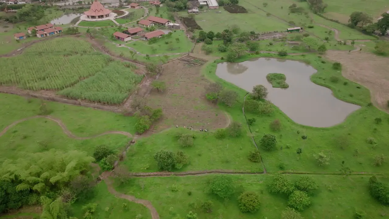 Slow aerial pan down of a group of people walking on a trail behind the Baha’i House of Worship in Cali Colombia