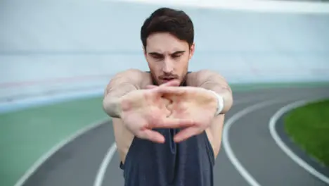 Sportsman stretching arms on track Sport man exercising before workout on track