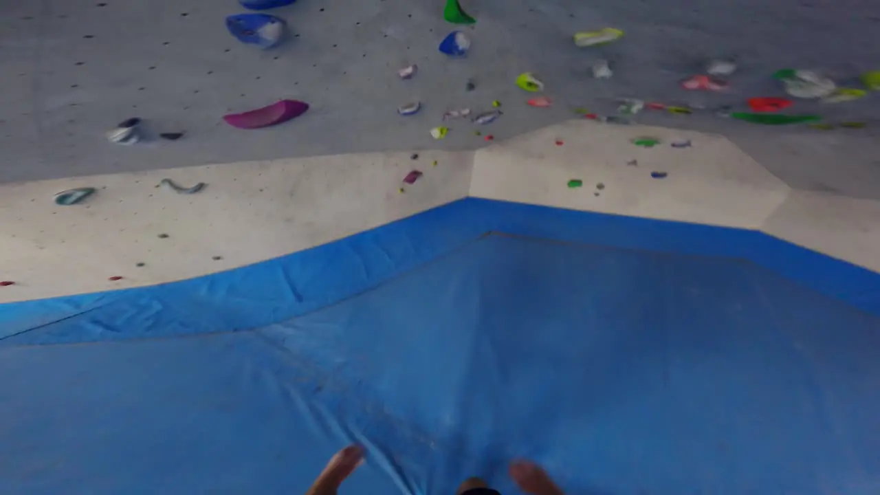 Tattooed climber training in artificial climbing wall inside a gymnasium in first-person view