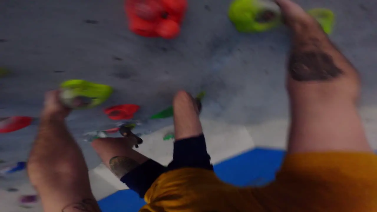 Tattooed climber trains on an overhang artificial climbing wall in POV