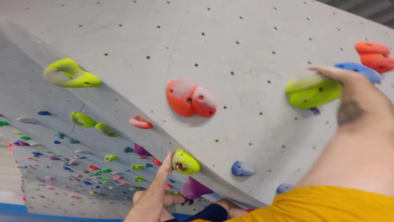 POV shot of a man with tattoos climbing in a bouldering gym