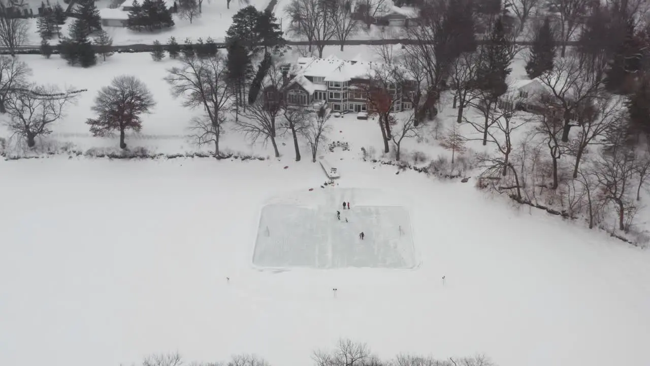 Aerial family and friends ice skating in backyard pond ice rink