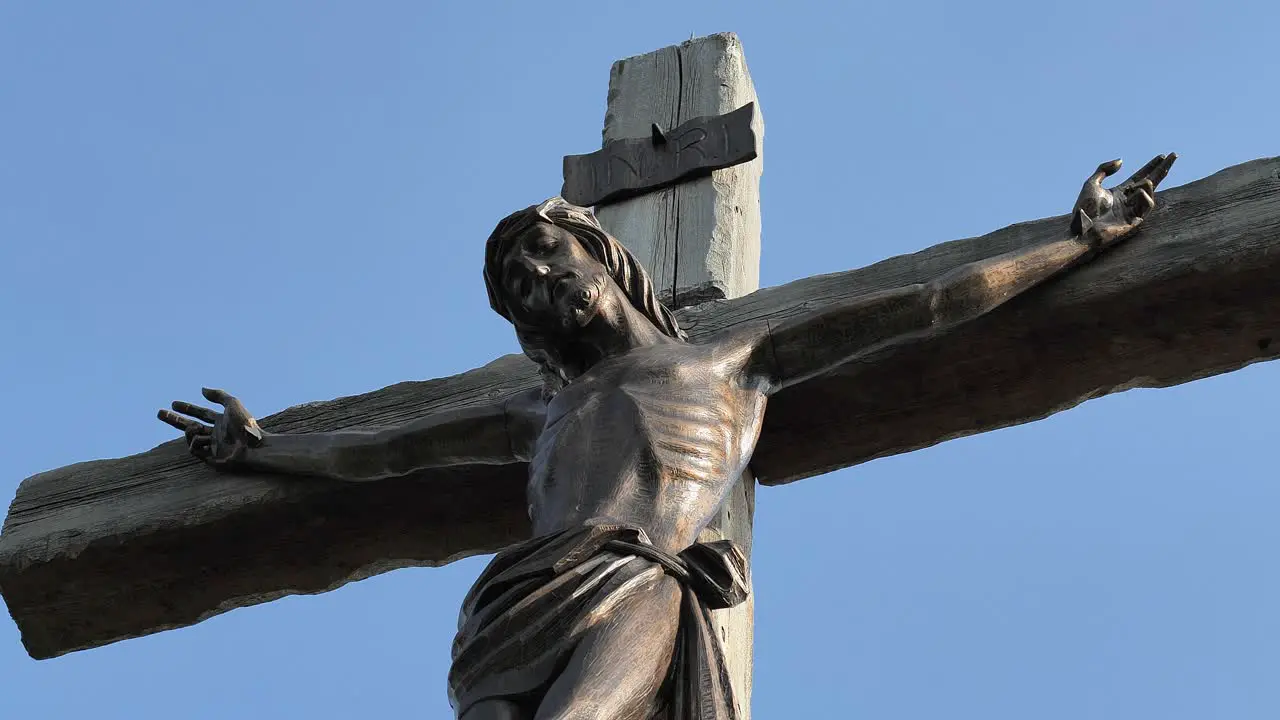 A bronze statue of the Crucifixion of Jesus in the sunset