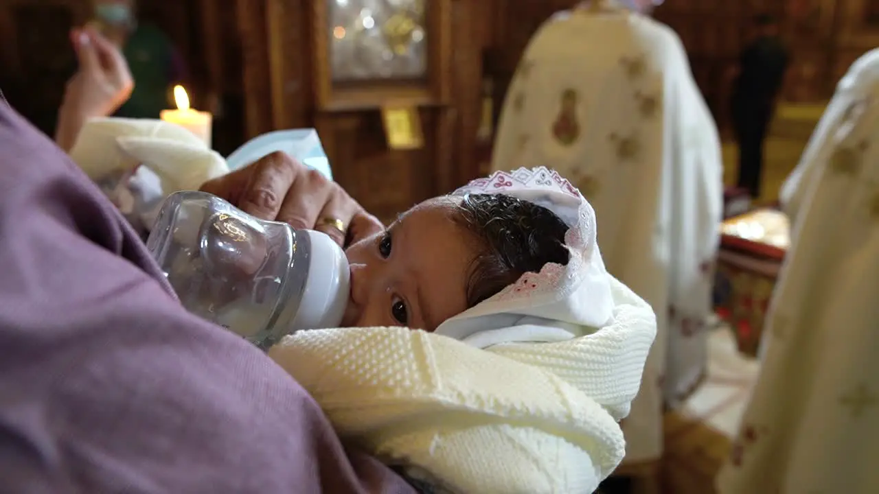 Newborn drinking milk during christening at church in Romania