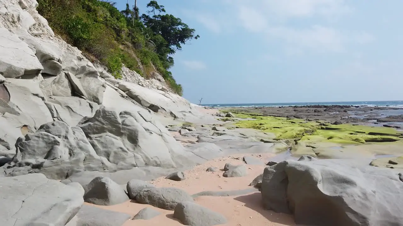 From behind a chalky rock to a full view of the unusual beach of a tropical remote island at low tide in the Andaman sea