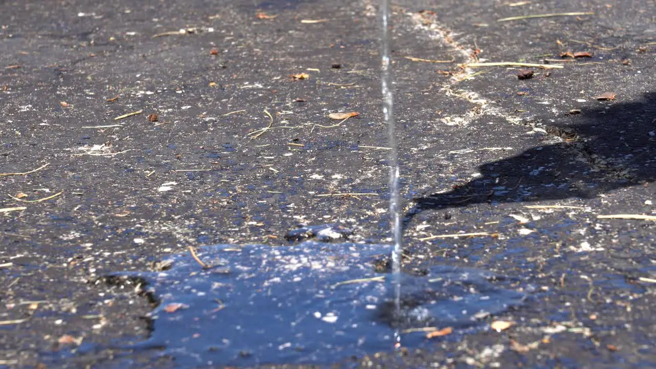 A high angle of water on warm blacktop cement in the summer sun