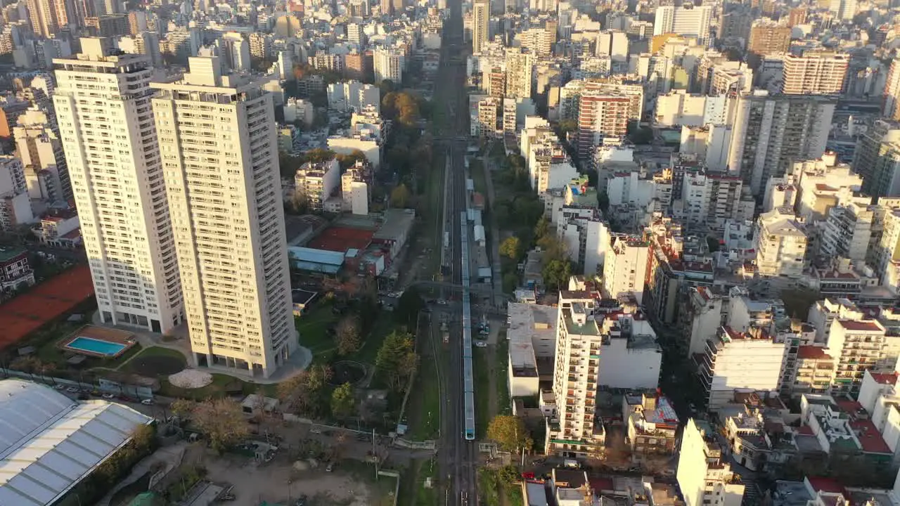  Dynamic aerial perspective of a train weaving through the heart of the city enveloped by urban buildings