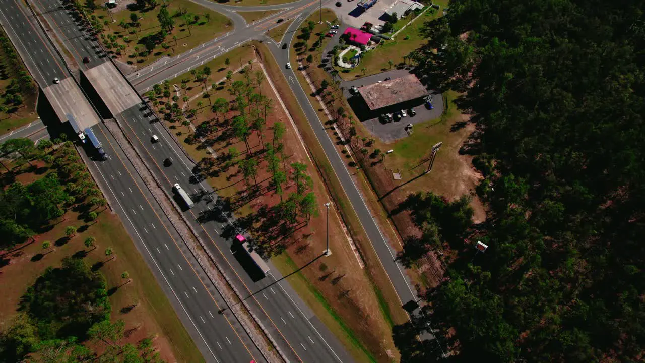 Aerial view of trucks on highway near logistics hub with warehouses and green landscape