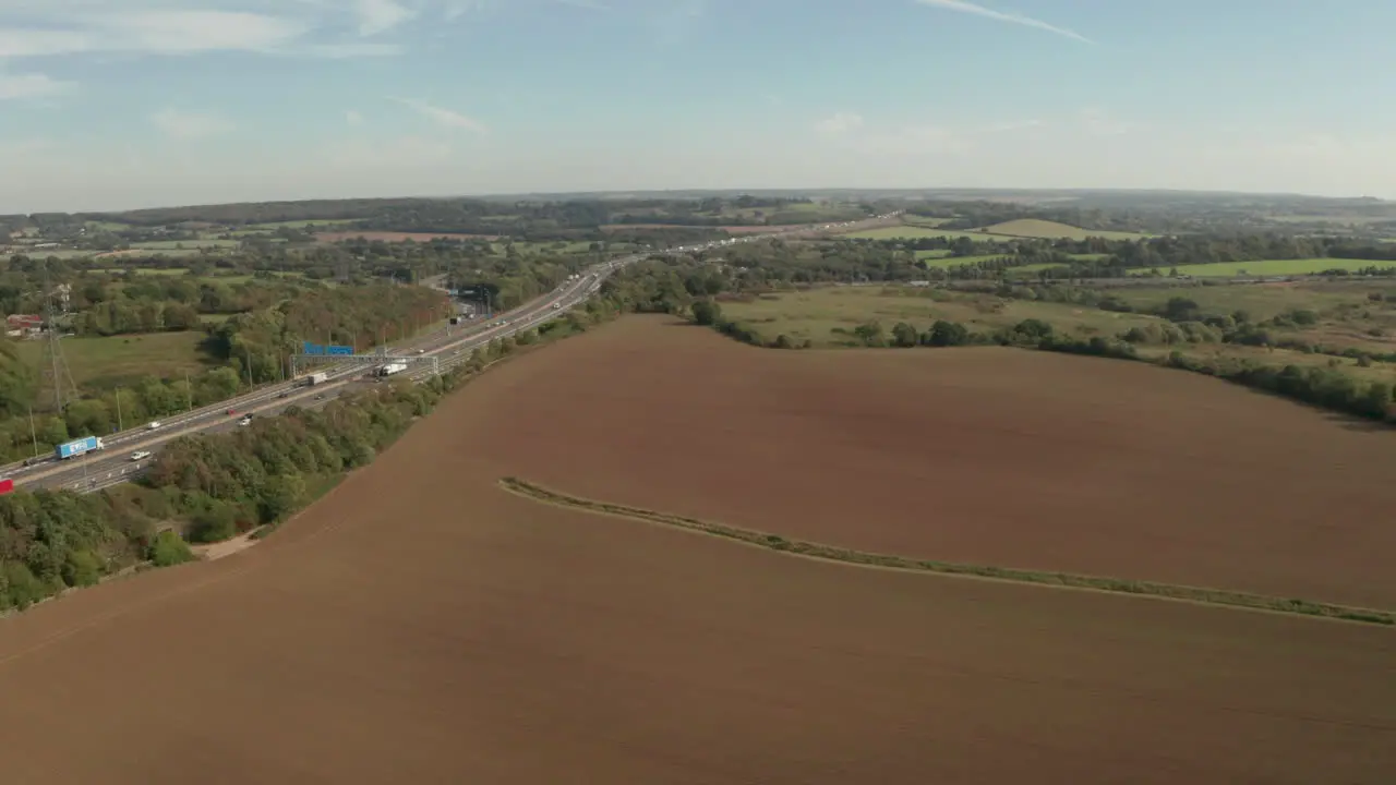 Aerial shot over farm land towards M25 motorway