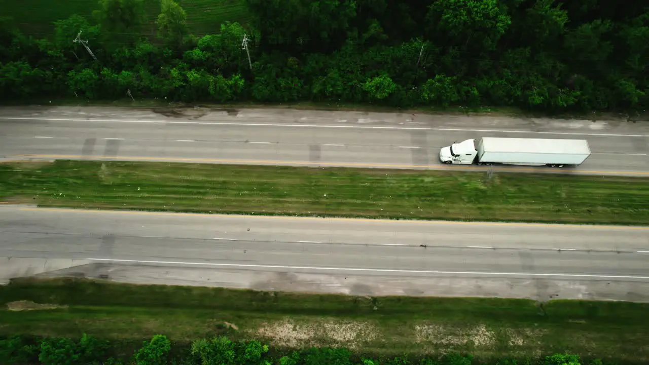 unique aerial of a semi truck and trailer turning left sorounded by green foliage