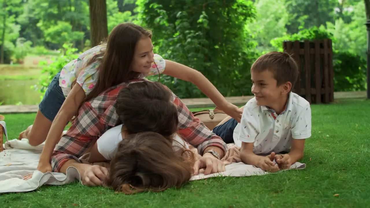 Family lying on blanket in park Parents having fun with children in forest