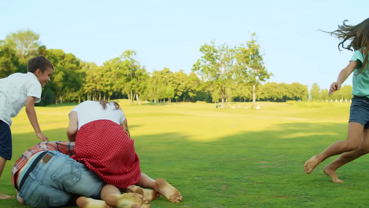 Positive family playing with ball in meadow Happy man throwing ball to girl