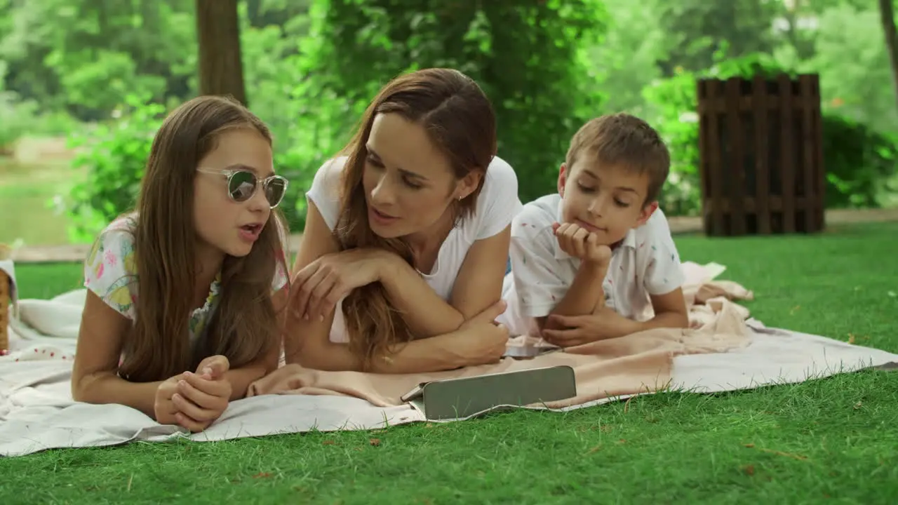 Mother with children looking at tablet screen in park Family using pad outside