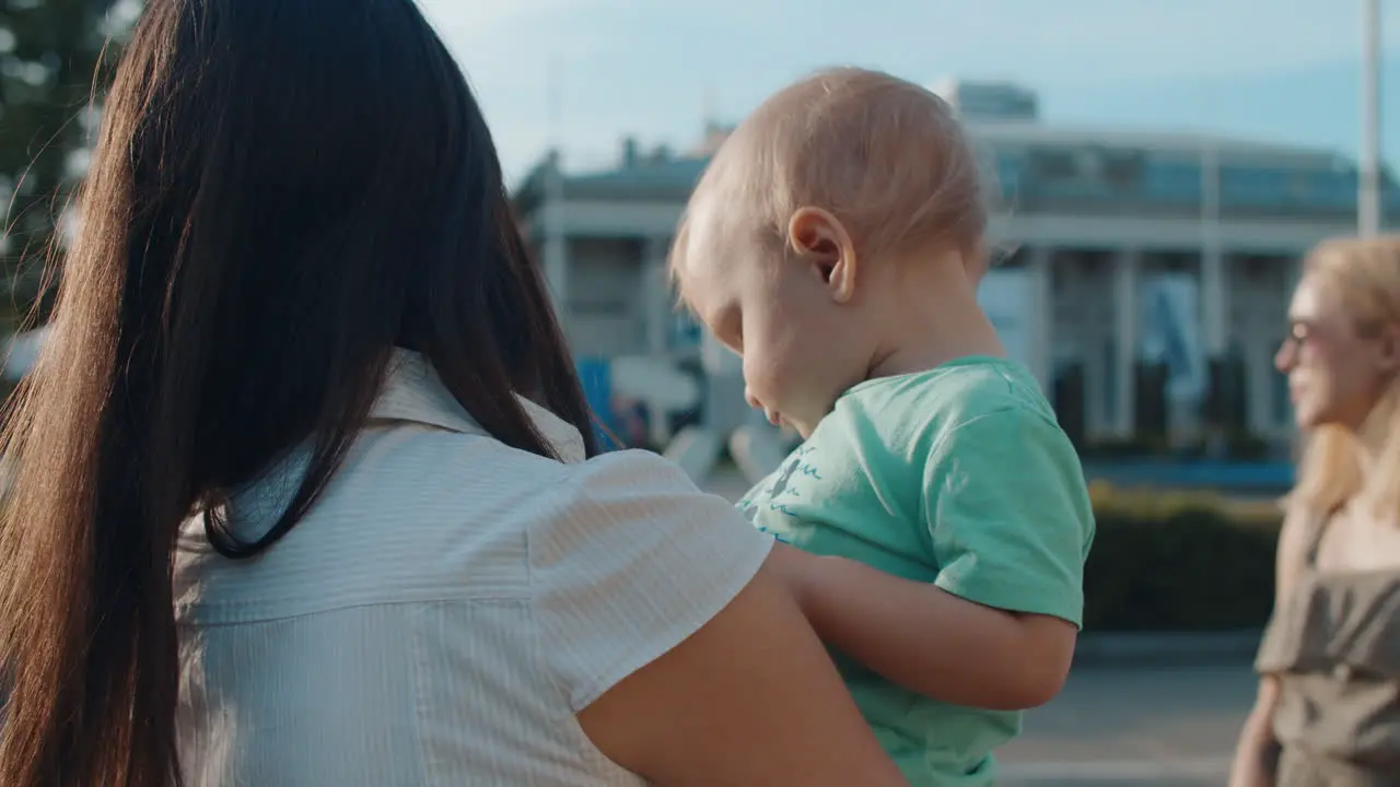 Young woman with kid on hands Beautiful mother and baby in amusement park