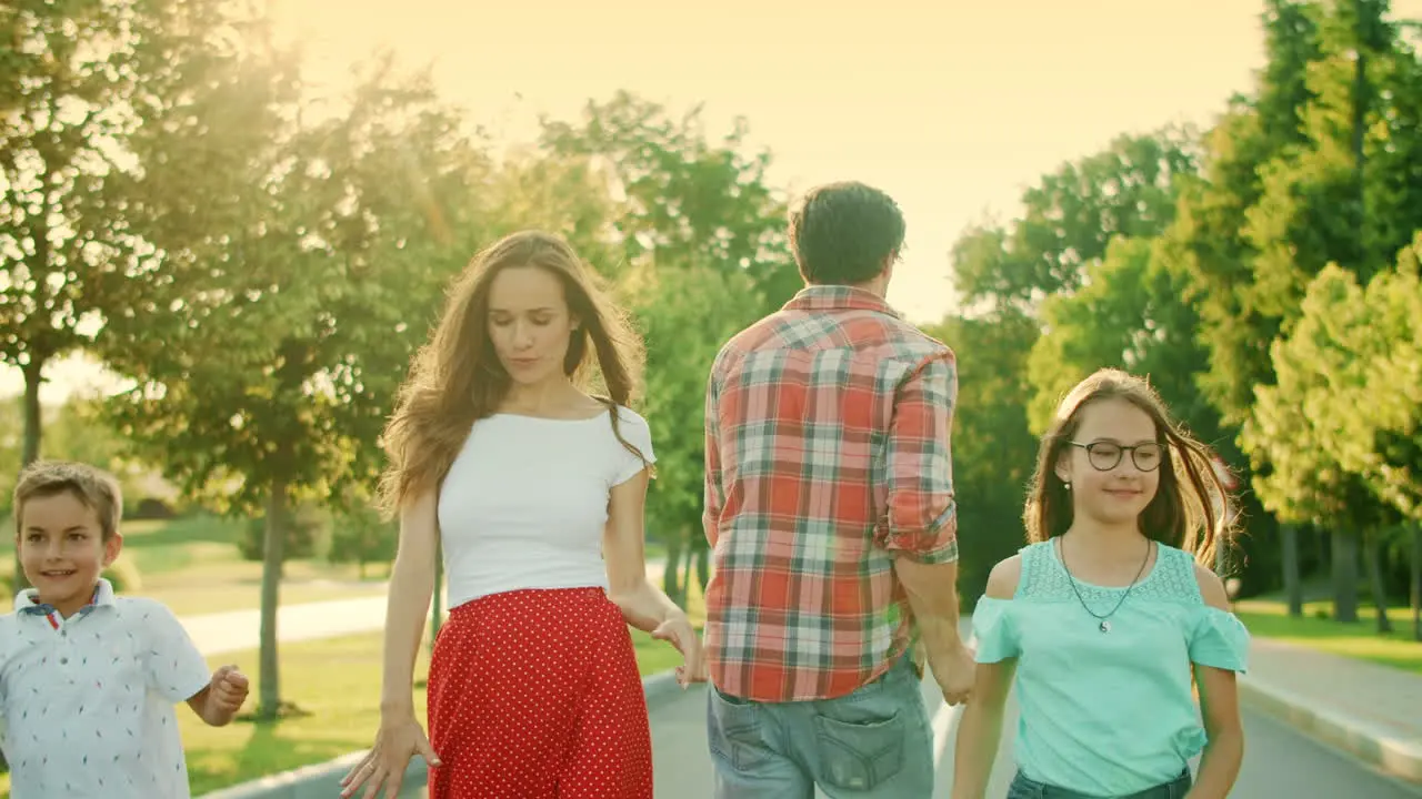 Positive parents and kids walking on street Happy family dancing outdoors