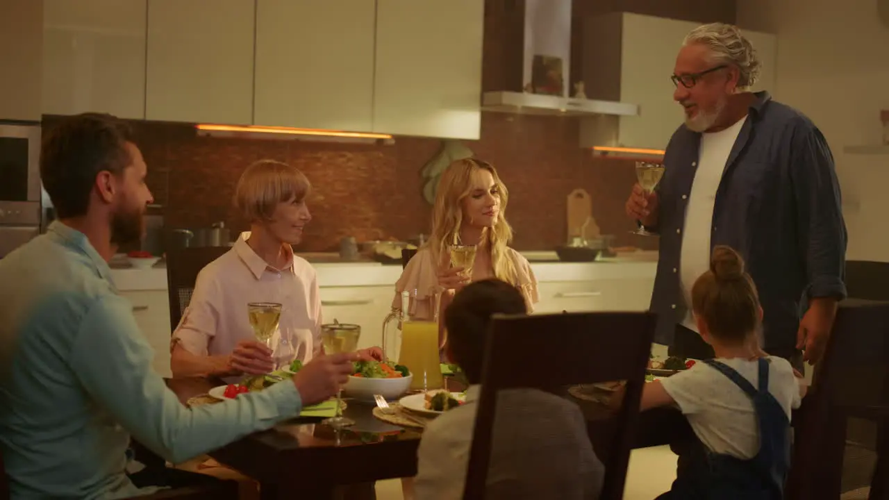 Family having dinner at home Senior man making toast with glass of wine