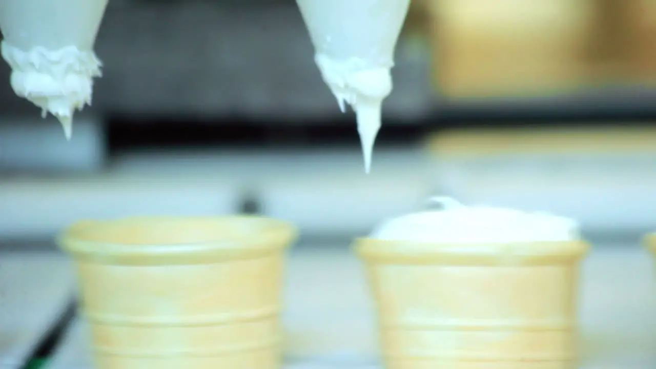 Automated production line Closeup of ice cream pouring in waffle cup at factory