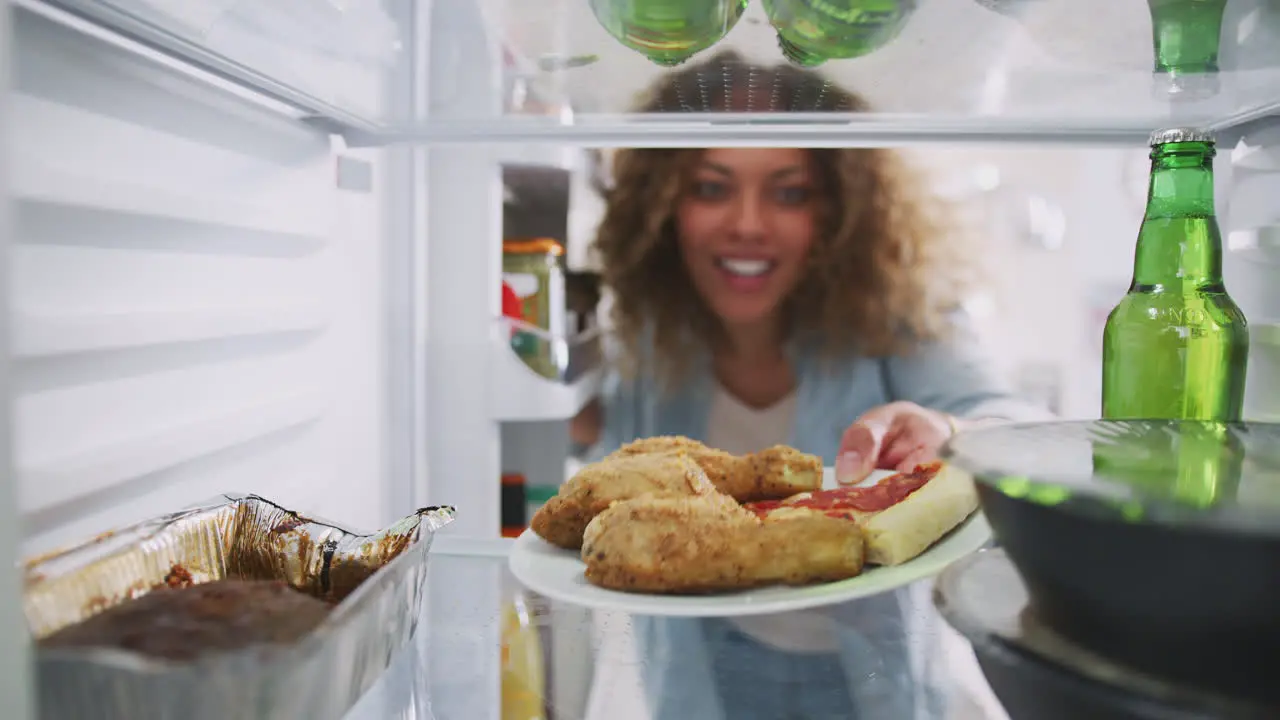 View Looking Out From Inside Of Refrigerator Filled With Takeaway Food As Woman Opens Door